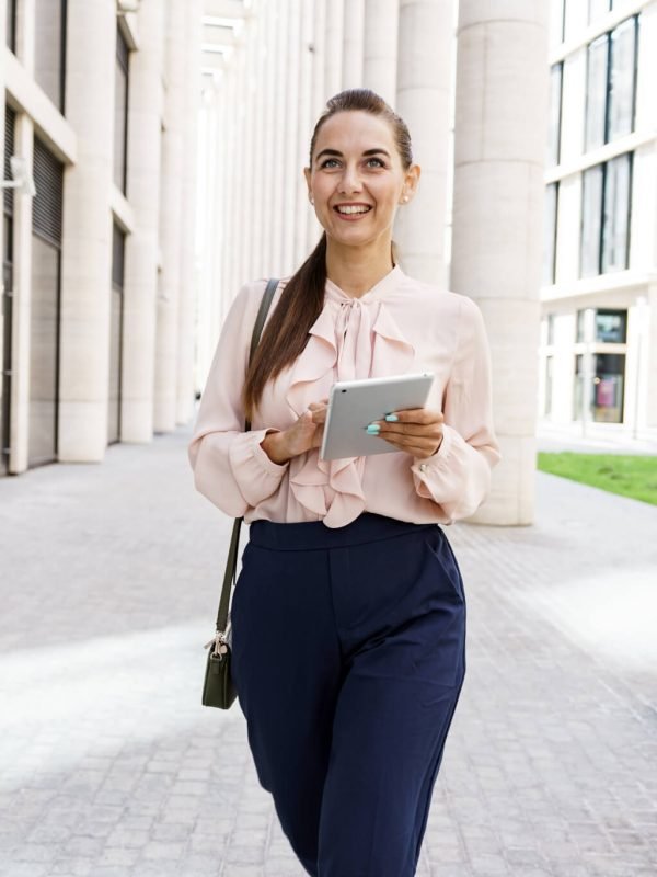 Mujer sonriente caminando con una Tablet en sus manos.